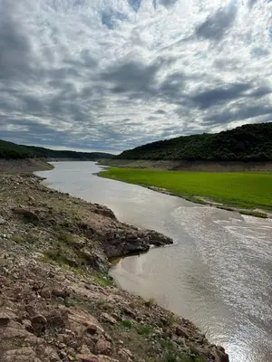 a river with rocks and grass on the side at Cabañas Ocho Soles in Las Rabonas
