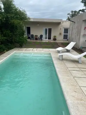 a swimming pool with two chairs and a house at lo de lucio in Almafuerte
