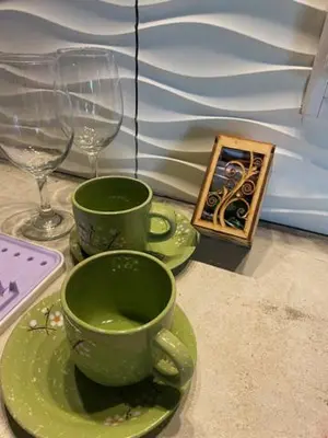 two green cups on a table with glasses and a book at lo de lucio in Almafuerte