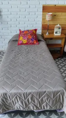 a gray bed with a pillow and a table at Casa Olivia Habitación privada in Alta Gracia