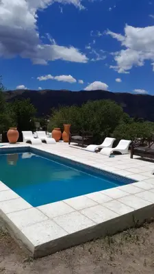 a swimming pool with lounge chairs and a view of the mountains at Colinas Del Mirador in Villa Carlos Paz
