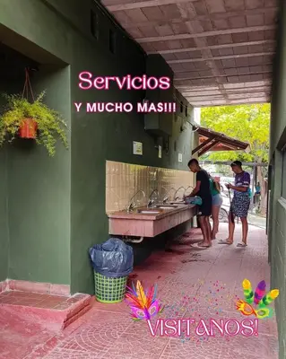 two people standing in front of a kitchen with sinks at La Ribera Hotel Dormis Camping in Villa Carlos Paz