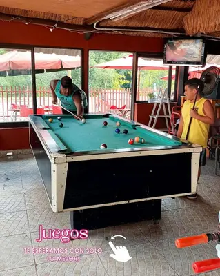 two men playing pool in a pool table at La Ribera Hotel Dormis Camping in Villa Carlos Paz