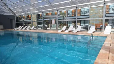 a large swimming pool with white lounge chairs in a building at BlackStone Apart Boutique Hotel in Villa General Belgrano