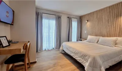 a hotel room with a bed and a desk and a bed sidx sidx sidx at BlackStone Apart Boutique Hotel in Villa General Belgrano
