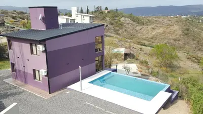 a purple house with a swimming pool in front of it at Alta Morada in Villa Carlos Paz