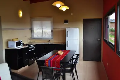 a kitchen with a table with chairs and a white refrigerator at Alta Morada in Villa Carlos Paz