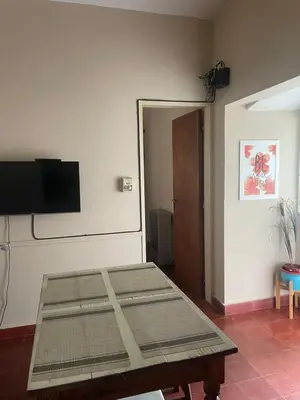 a room with a table and a flat screen tv at Comodo departamnto con asador in Villa Carlos Paz