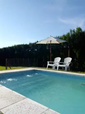 a swimming pool with two chairs and an umbrella at INTI MAYU Cabañas in Mina Clavero