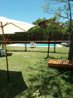 an umbrella and a bench next to a pool at INTI MAYU Cabañas in Mina Clavero