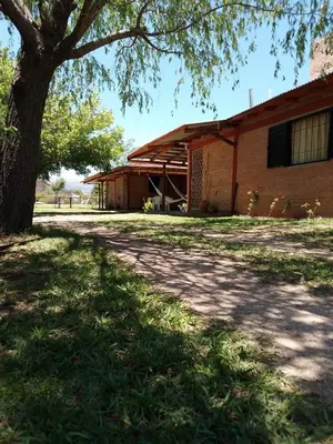 a building with a tree in front of it at INTI MAYU Cabañas in Mina Clavero