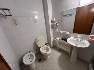 a white bathroom with a toilet and a sink at Alojamiento Buen Pastor in Cordoba