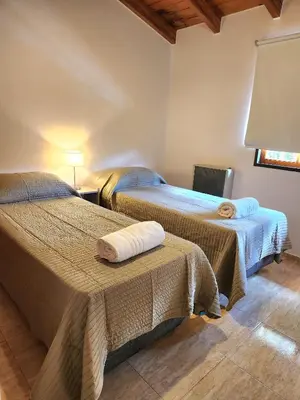 a hotel room with two beds and a window at Vacaciones Diferentes 25 de Mayo in Villa Carlos Paz