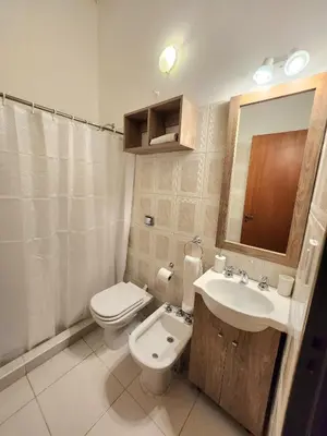 a bathroom with a toilet and a sink and a mirror at Vacaciones Diferentes 25 de Mayo in Villa Carlos Paz