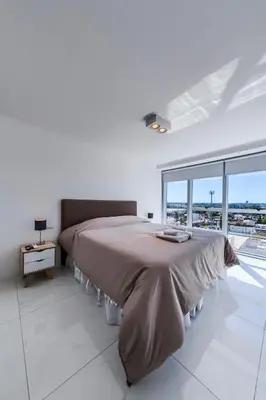 a large bed in a white room with a large window at La Diva de Gama in Cordoba