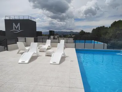 a row of white lounge chairs next to a swimming pool at Dpto en Carlos Paz con vista al Lago in Villa Carlos Paz