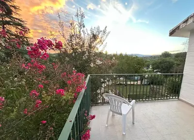 a white chair sitting on a balcony with pink flowers at Casa de Beto Estancia Vieja in Estancia Vieja