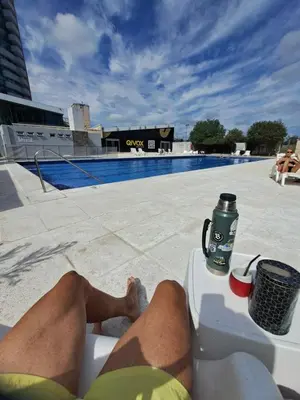 a person sitting on a chair next to a swimming pool at Vista al Kempes in Cordoba