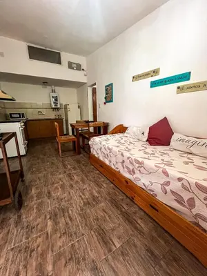a bedroom with a large bed and a kitchen at Depto 150 in Villa Carlos Paz