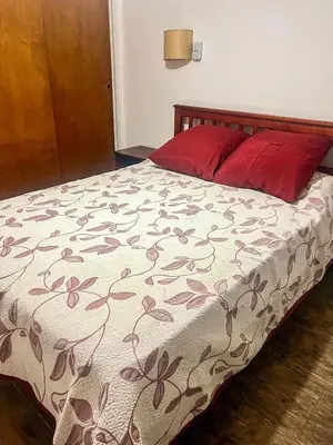 a bedroom with a bed with a red pillow at Depto 150 in Villa Carlos Paz