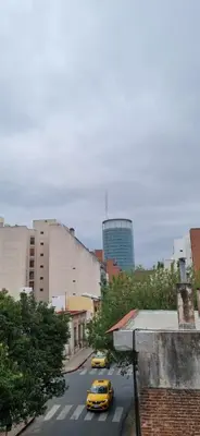 a yellow taxi driving down a city street with buildings at Dpto 1 RaGi in Cordoba
