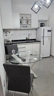 a kitchen with a glass table with two chairs and a refrigerator at Dpto 1 RaGi in Cordoba