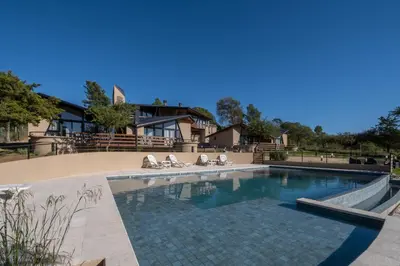 a swimming pool with chairs and a house at Bonaire Aparthotel in Villa General Belgrano