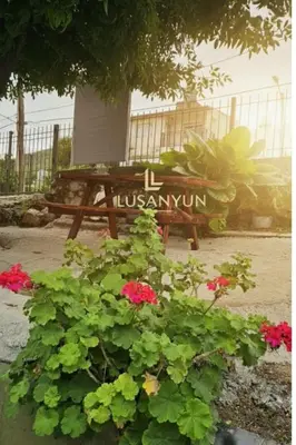 a bench in a garden with flowers and a sign at LUSANYUN 1 in Villa Independencia