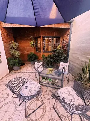 a patio with chairs and a table and a blue umbrella at Impecable departamento temporario en Córdoba in Cordoba