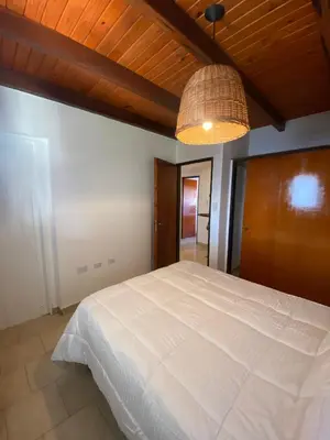 a bedroom with a large white bed and a lamp at Complejo Arenas in Alta Gracia