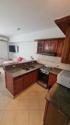 a kitchen with wooden cabinets and a stove top oven at Escaparte nunca se sintió tan bien, este es tu rincón para disfrutar in Villa Carlos Paz