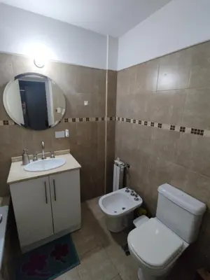 a bathroom with a toilet and a sink and a mirror at Departamento Alta Cordoba Lautaro II Dormitorios con Pileta in Cordoba