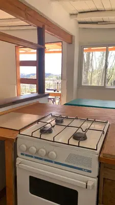 a stove top oven in a kitchen with two windows at Espejo Escondido in Tanti