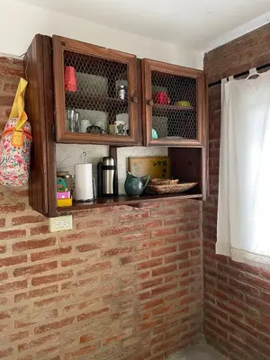a kitchen with wooden cabinets and a brick wall at Tila Huasi in Villa Icho Cruz