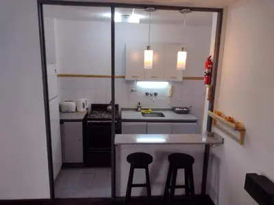 a small kitchen with two bar stools and a counter at Depto. Lindo Excelente Ubicación in Cordoba