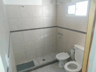 a bathroom with a toilet and a shower with a window at Talamochita in Santa Rosa de Calamuchita