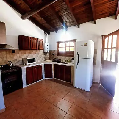 a kitchen with a white refrigerator and wooden cabinets at Cabaña Kiara VGB in Villa General Belgrano