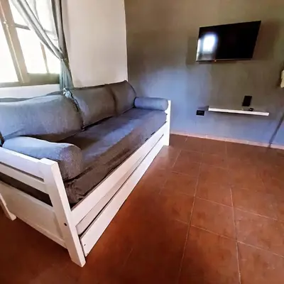 a couch sitting in a room with a tv at Cabaña Kiara VGB in Villa General Belgrano