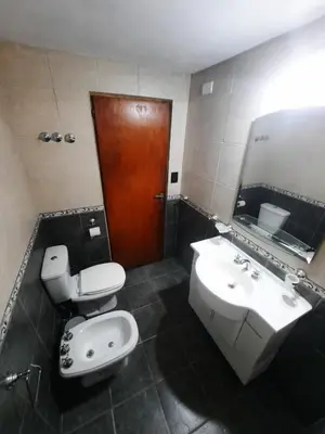 a bathroom with a toilet and a sink and a mirror at Cabaña Kiara VGB in Villa General Belgrano