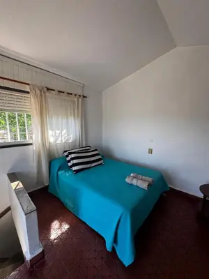 a blue bed in a white room with a window at La Chuña in Villa Los Aromos