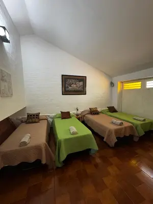 a room with three beds with green sheets at La Chuña in Villa Los Aromos