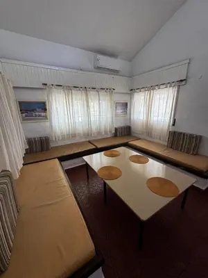 a living room with tables and chairs and windows at La Chuña in Villa Los Aromos