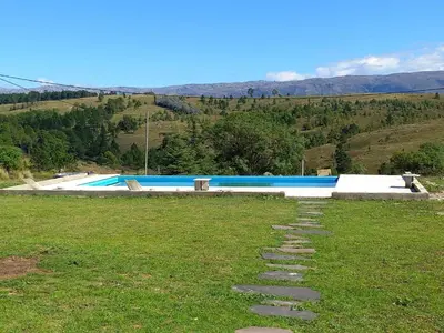 a swimming pool with stepping stones in a grass field at Las Calandrias in La Cumbrecita