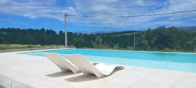 two white chairs sitting next to a swimming pool at Las Calandrias in La Cumbrecita