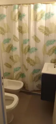 a bathroom with a shower curtain with a toilet and a sink at Hermoso en Plaza Alberdi in Cordoba