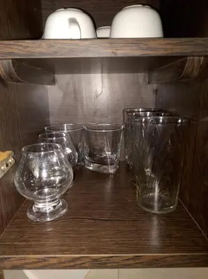 a shelf with several glass bowls and vases on it at Departamento céntrico in Río Cuarto