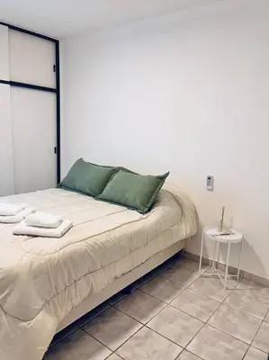 a bed with green pillows and a table in a room at Nueva Cordoba a metros de Palacio Ferreyra in Cordoba