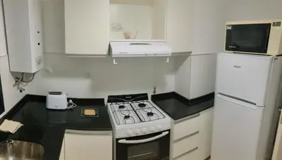 a kitchen with a stove and a white refrigerator at Departamento Nueva Cordoba in Cordoba