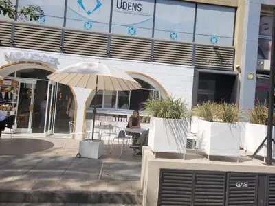a woman sitting at a table with an umbrella in front of a building at Departamento Nueva Cordoba in Cordoba