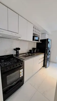 a kitchen with white cabinets and a black stove top oven at Apartamento -Diva- Complejo 